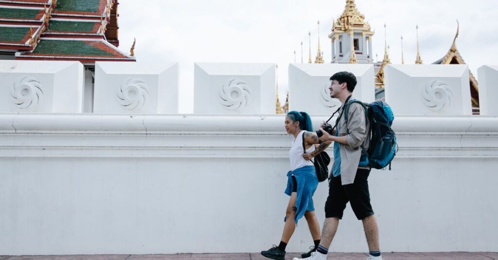 Travelers walking hands-free with small daypacks past Thai temple architecture