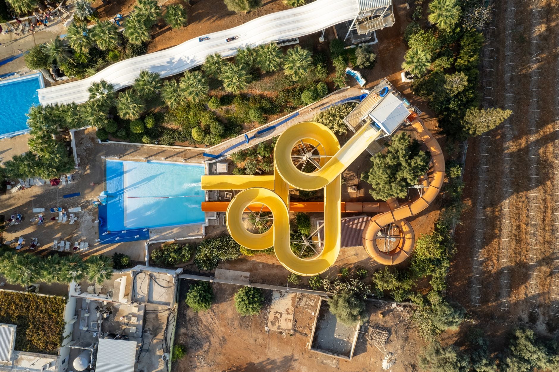 Aerial view of a water park showing looping slides, a wave pool and palm trees