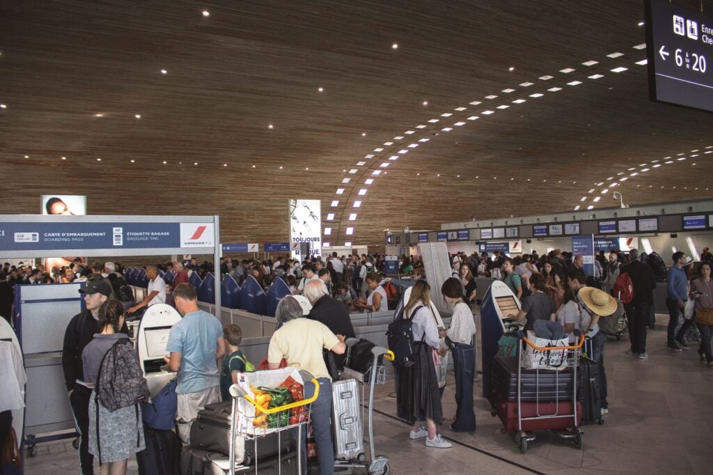 Crowded airport check-in queue with luggage trolleys
