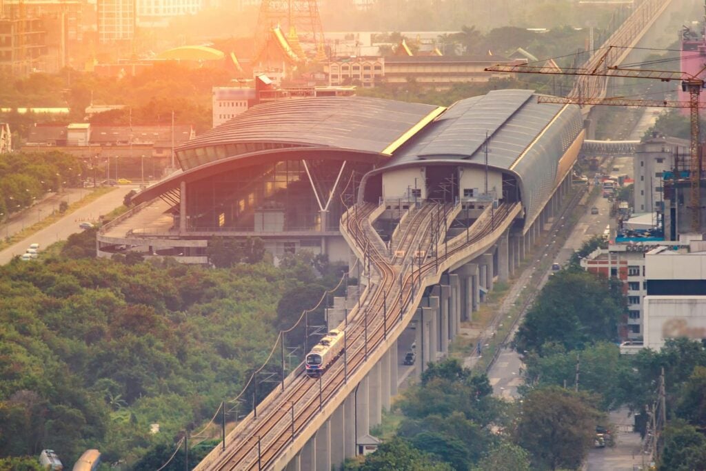 An Airport Rail Link train on the elevated line approaching a large station in Bangkok